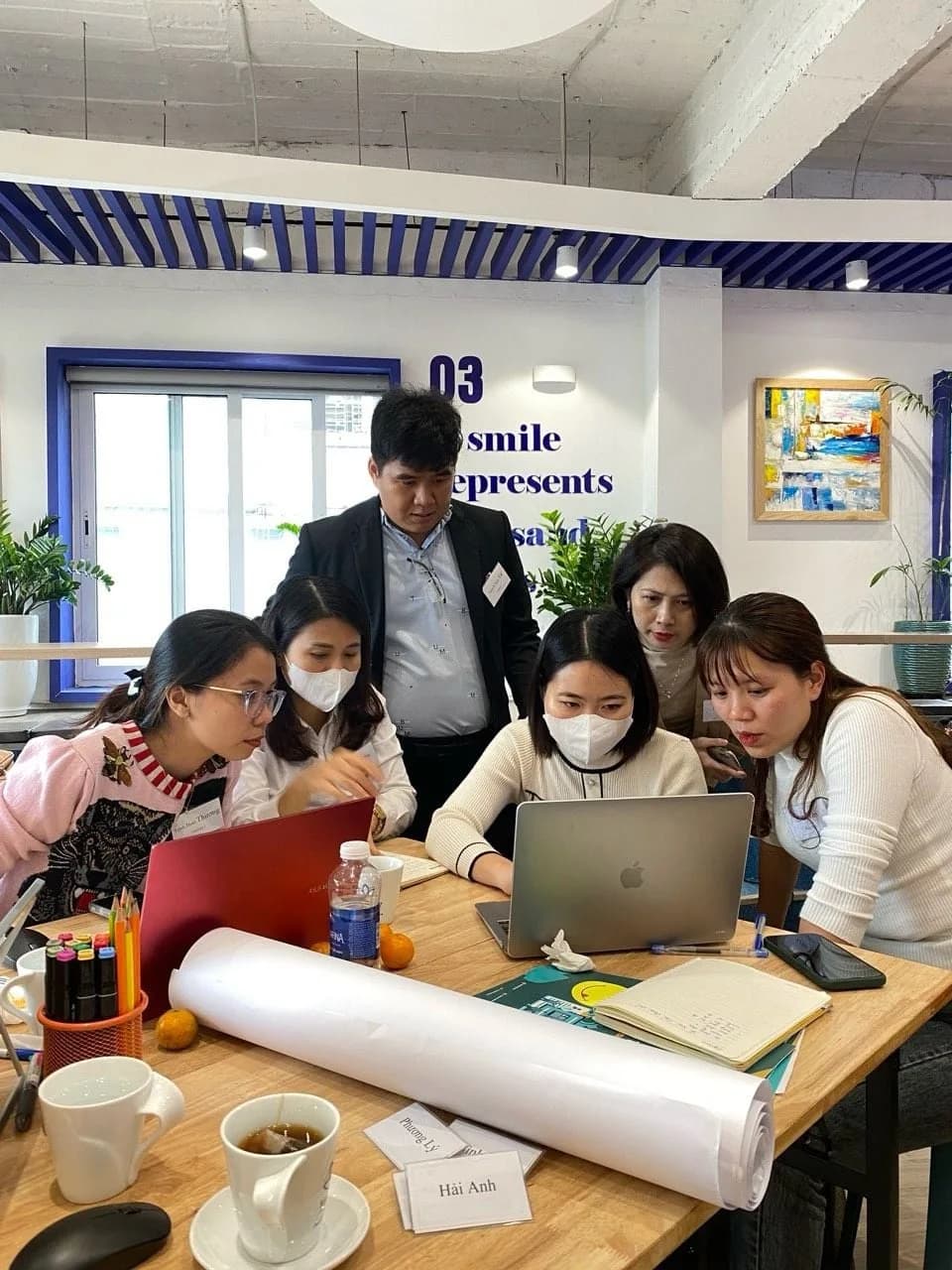 Nhóm làm việc quanh máy tính và bản vẽ sơ đồ trải trên bàn